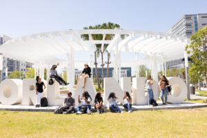 Students sitting on and around an Orlando sign at a park